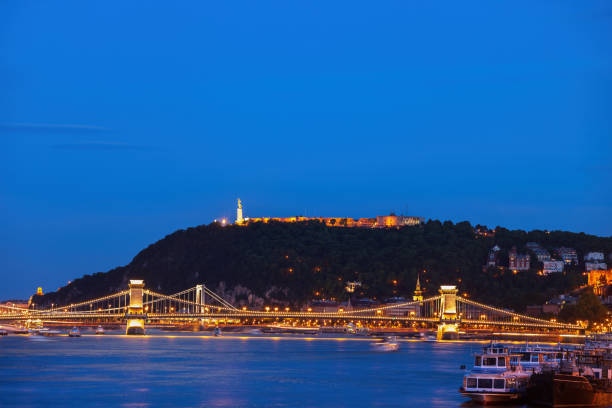 Gellert Hill River View In Budapest City At Night Gellert Hill with Citadel in Budapest at night, illuminated bridges on Danube river, capital city of Hungary gellert stock pictures, royalty-free photos & images