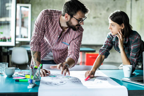 istock Young creative couple talking while working on business plans in the office. 1224303741