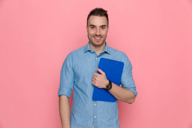 istock casual man holding his clipboard to chest, smiling 1224304524