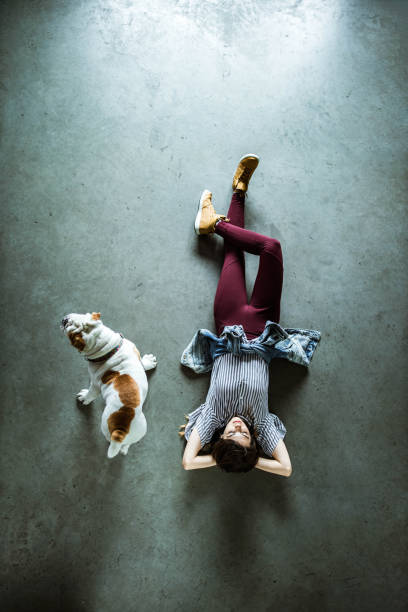 sopra la vista di una donna rilassata sdraiata sul pavimento accanto al suo cane. - lying on the floor foto e immagini stock