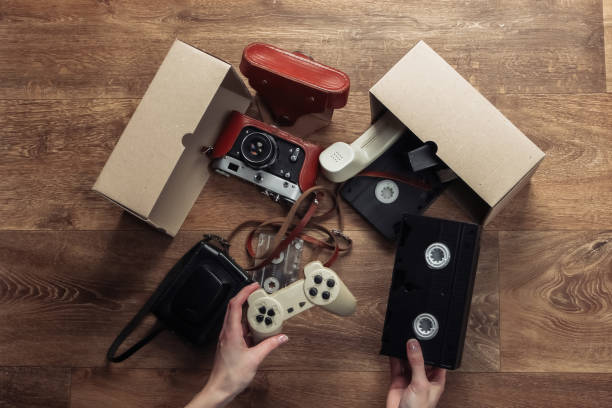 istock Female hands stack Retro objects in a cardboard box on a wooden floor. Antiques, vintage. Top view 1224308280
