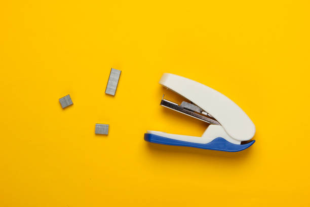 Stapler with paper clips on yellow background. Minimalism. Top view