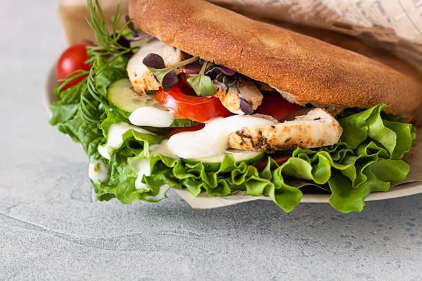 istock Pita bread sandwich with fresh vegetables and roasted chicken. Light grey stone background. Healthy snack. Takeaway food, street fast food. 1224309595
