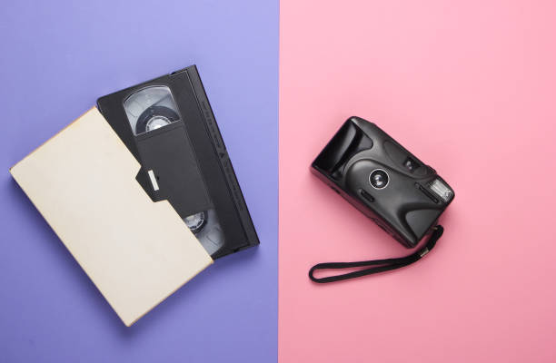 istock Video cassette and retro camera on pink-purple pastel background. Top view 1224309762