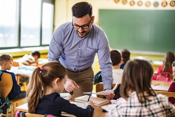istock Young happy professor assisting his elementary students on a class at school. 1224310194