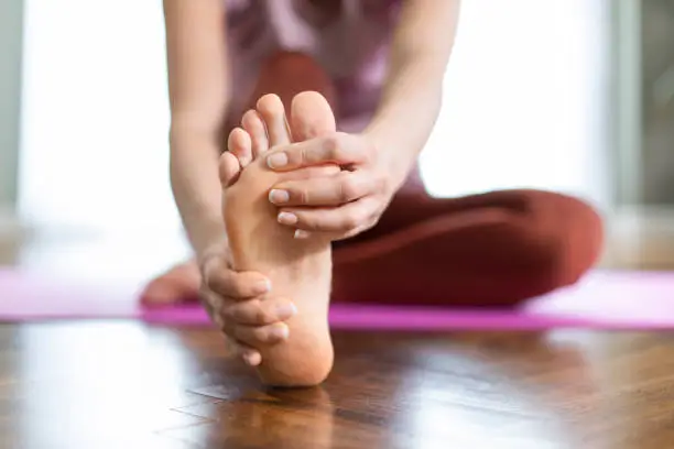 Photo of Young sporty woman feeling pain in her foot