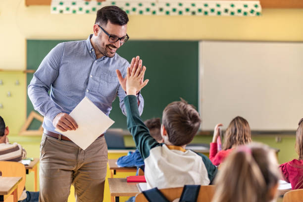 happy teacher and schoolboy giving each other high-five on a class. - elementary student classroom education elementary school building imagens e fotografias de stock