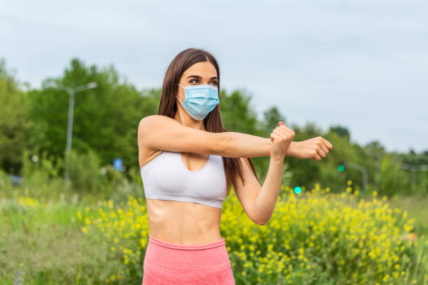 美しい若いフィットネススポーツの女性が実行する前にウォーミングアップし、彼女は都市、コロナウイルス、covid - 19保護の保護ダストと汚染のためのマスクを着用しています - toxic substance dirt pollution scientific experiment ストックフォトと画像