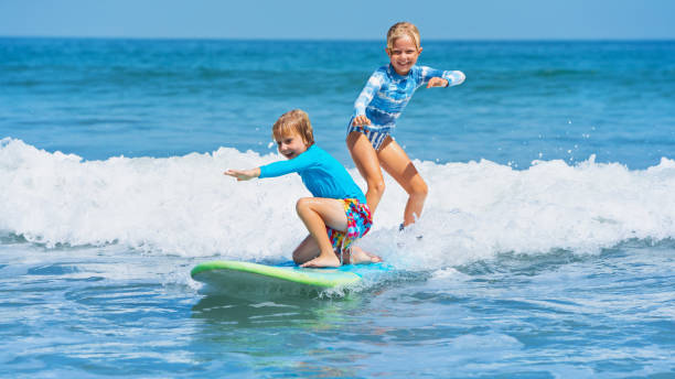 istock Two young surfers ride with fun on one surfboard 1224314637
