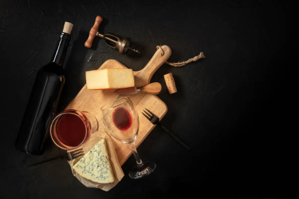 istock Wine and cheese tasting, top shot on a black background with a place for text, with a cork, corkscrew, and a bottle 1224316155
