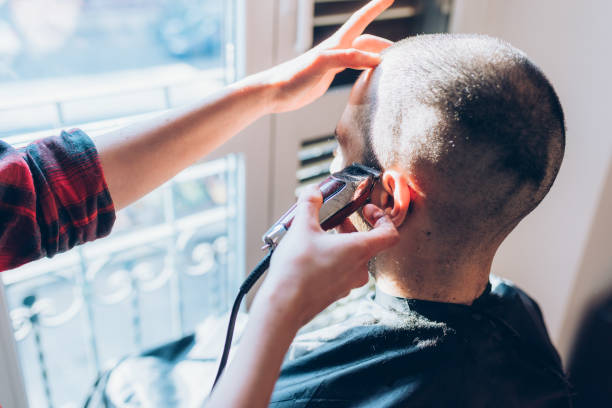 istock Woman barber cutting hair using razor 1224317659