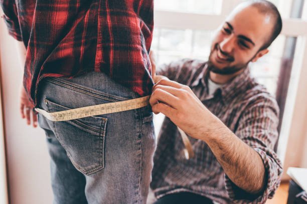 istock Young caucasian male fashion designer working on garment on a model, using yardstick 1224317721