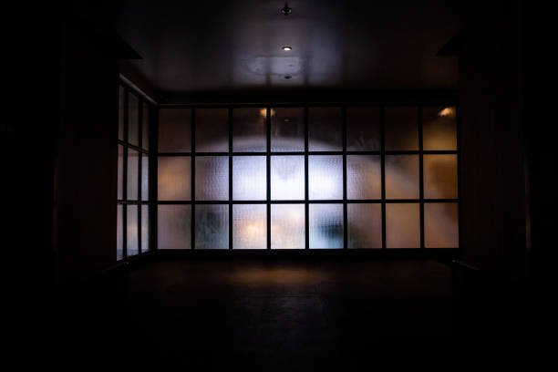 istock Frosted glass wall with black metal frame in grid pattern with bright light from the inside looking from the hallway. 1224319320
