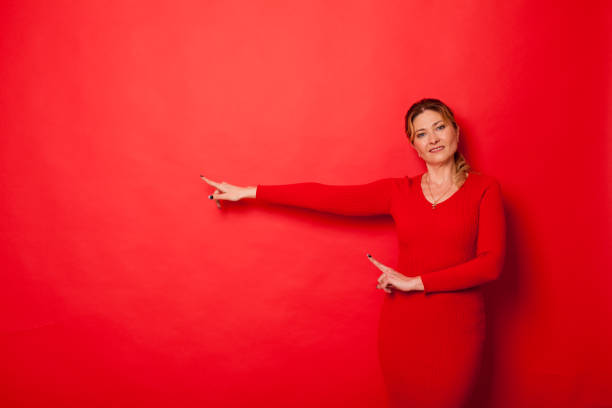 mujer cuarenta años en un vestido sobre un fondo rojo - 35 40 years fotografías e imágenes de stock