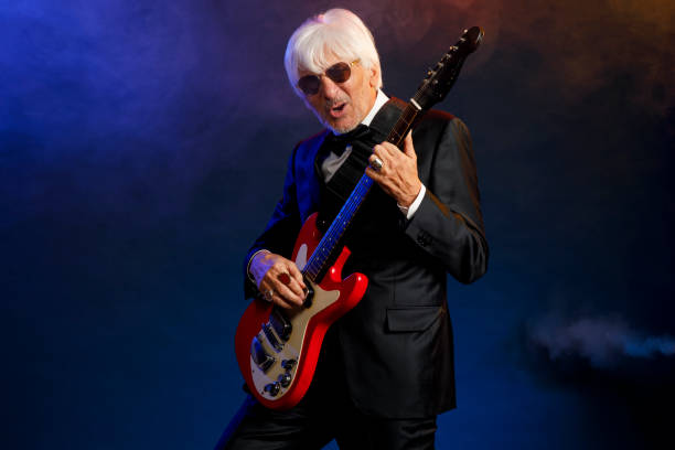 istock Musician Guitarist Active senior Handsome man playing guitar. Blue  background, with rays of light and special effects smoke. 1224322023
