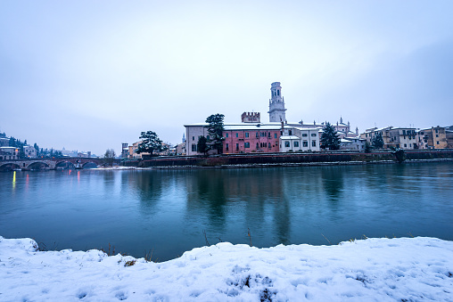 River Adige and Verona cityscape with the Ponte Pietra (Stone bridge, 1st century B.C.) and the bell tower of the Cathedral in winter with snow. Veneto, Italy, Europe