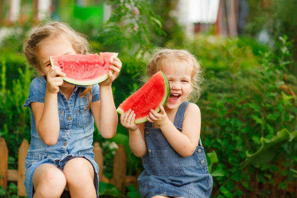 istock Little girls sit on watermelon and keep pieces 1224322373
