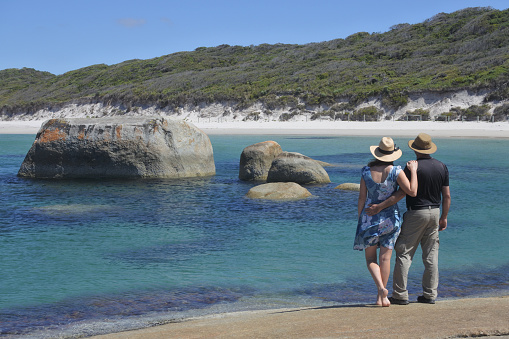 Australian couple looking at the landscape view of Greens Pool beach with boulders on the south coast of Western Australia between Denmark and Walpole.