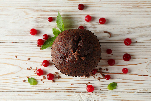 Chocolate muffin and berries on white wooden background