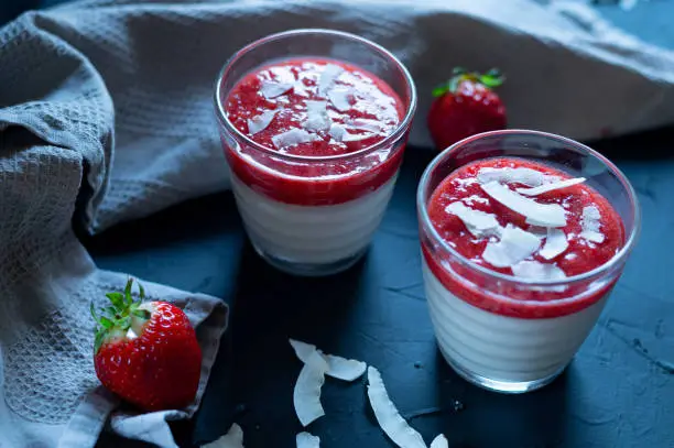 vegan recipe concept with coconut pannacotta with strawberry fruit pulp and coconut flakes