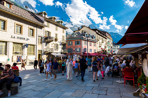 Chamonix, France - 5 August, 2019: color image depicting crowds of people exploring the quaint summer streets of Chamonix in southern France, in the foothills of the Alps and Mont Blanc. People are exploring the town and eating and drinking at the many cafes and restaurants in this charming mountain resort.