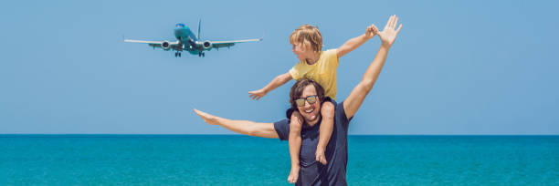 padre e figlio si divertono sulla spiaggia a guardare gli aerei da sbarco. viaggiare su un aereo con bambini concetto banner, formato lungo - travel agent foto e immagini stock