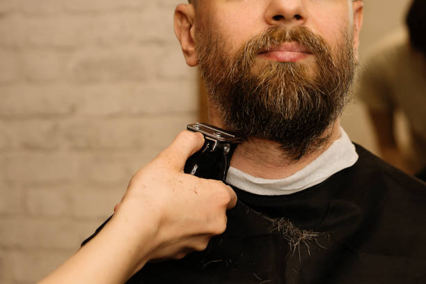 istock Barber trimming beard with electric razor 1224332852