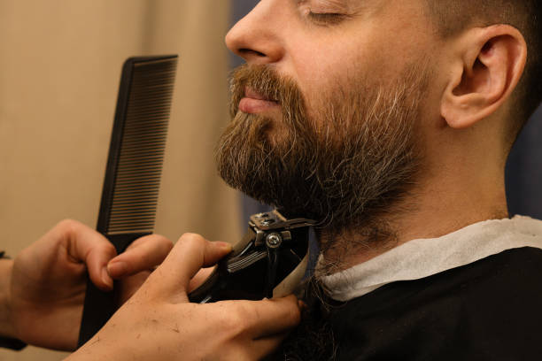istock Barber trimming beard with electric razor 1224332855