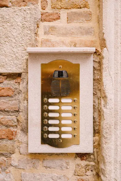Photo of Close-ups of building facades in Venice, Italy. An old vintage intercom and a mailbox on a stone wall. On door where placed this old rusty doorbells.