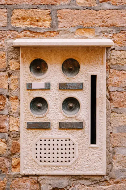 Photo of Close-ups of building facades in Venice, Italy. An old vintage intercom and a mailbox on a stone wall. On door where placed this old rusty doorbells.