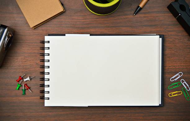 istock A blank white page of a spiral notepad over brown wooden table surface, surrounded by stationery objects. 1224337414