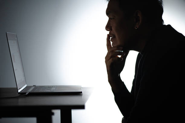 istock Silhouette asian man Working on Laptop. Beared man Works from home on Notebook. Freelancer man Blogger Working remotely at Home With Laptop. A Man looking and focusing face. 1224338099