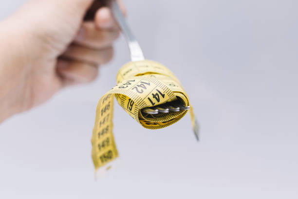 tape measure simulating ready-to-eat food with cutlery - anorexia imagens e fotografias de stock