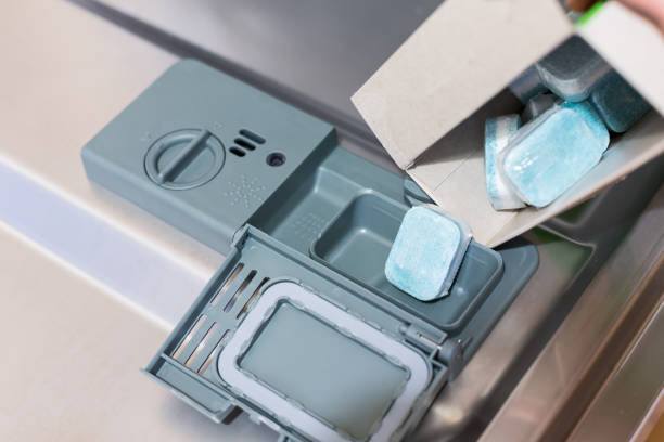 istock Man fills eco tablets detergent in dishwasher. Disposable tablets in plastic that dissolves. 1224340113