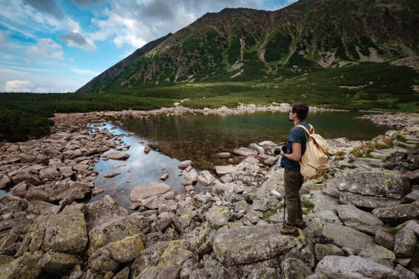 Man Traveler with backpack near mountain lake . Travel Lifestyle concept. Travel and active life concept with team. Adventure and travel in the mountains region in the Poland Tatri