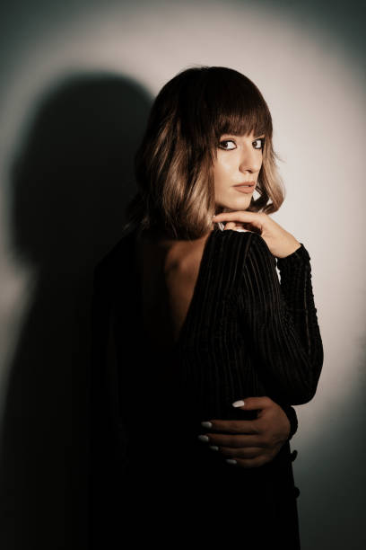 Portrait beautiful woman with attitude wearing black clothes posing while looking at camera with shadow in the background