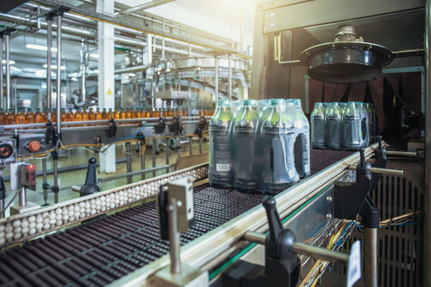 cinta transportadora o línea con botellas de jugo empaquetadas y lista para entregar o enviar en maquinaria de equipos de fábrica de bebidas - bottling plant industry drink food processing plant fotografías e imágenes de stock