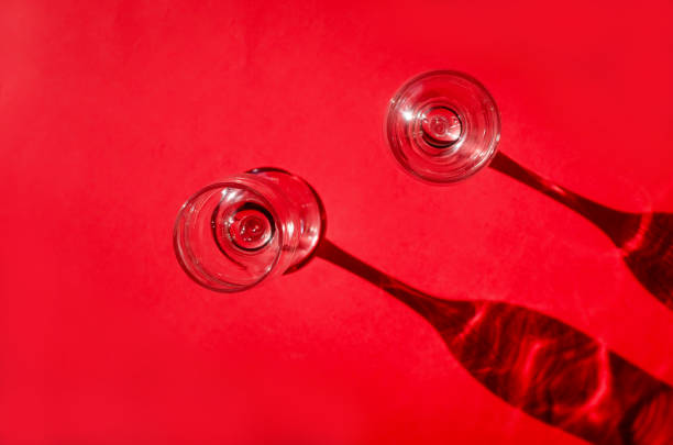 istock Two empty glasses with shadows on red background in natural sunlight . 1224346802