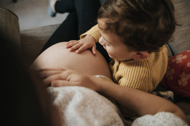 garçon touchant le ventre de sa mère enceinte - abdomen adult affectionate baby photos et images de collection