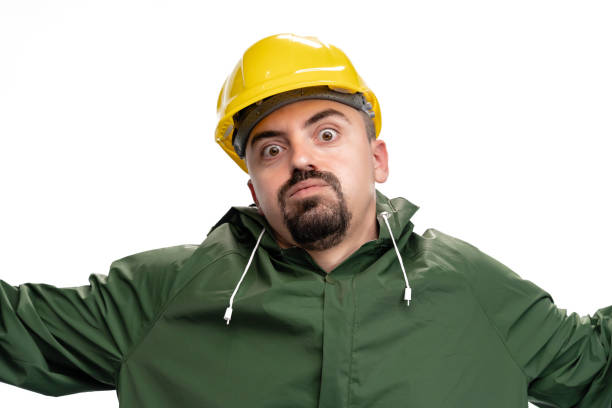 Angry engineer with green raincoat and hardhat using smartphone on white background. Photo is taken in studio environment with Sony A7III camera