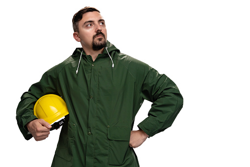 Portrait of young male engineer or worker, holding his helmet on white background. Photo is taken in studio environment with Sony A7III camera