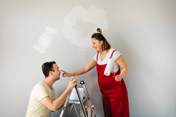 young couple choosing the right color for their wall while renovating apartment. - paint home improvement paint can decorating imagens e fotografias de stock
