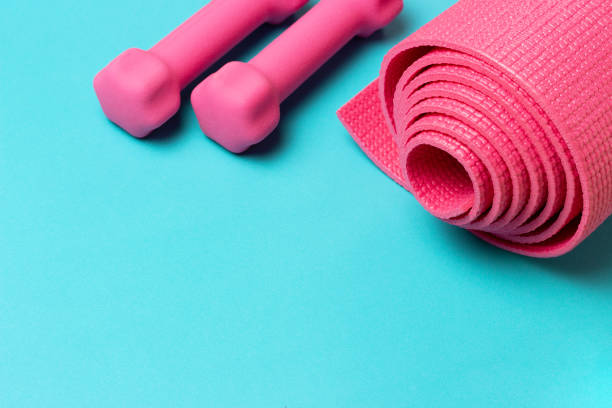istock Sports mat and pink dumbbells on blue background, copy space 1224359036