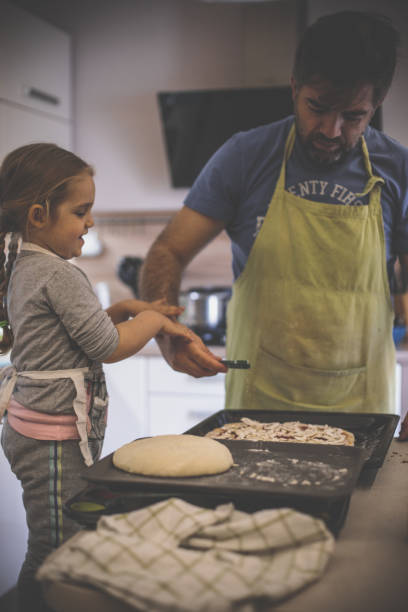 istock Father and daughter adding oregano to homemade pizza 1224359059