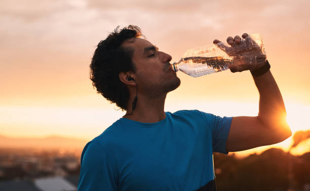 Fuel your workout with water Shot of a young man drinking water during a workout in the city at sunset center athlete stock pictures, royalty-free photos & images