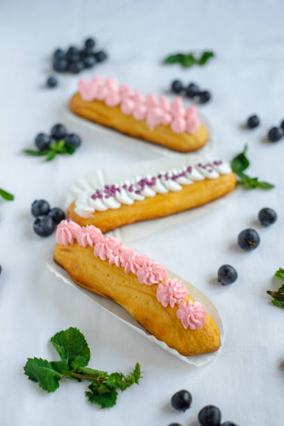 istock Tasty homemade eclairs on a white tablecloth. Blueberries are scattered everywhere. 1224367632