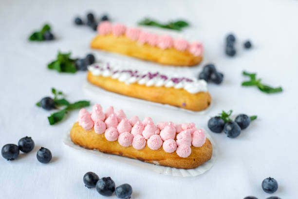 istock Tasty homemade eclairs on a white tablecloth. Blueberries are scattered everywhere. 1224367730