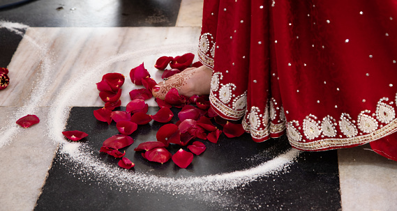 bride in a red Sari. Beautiful traditional Indian wedding ceremony. the bride takes a step into the circle saying the vow. Hindu wedding. indian engagement. Hindu the Vedic Yagya ceremony. vivah Yajna
