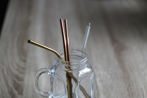 Reusable metal straws and cleaner in a glass jar. Selective focus.