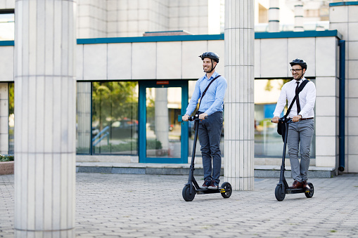 Businessmen riding electric scooters in the city